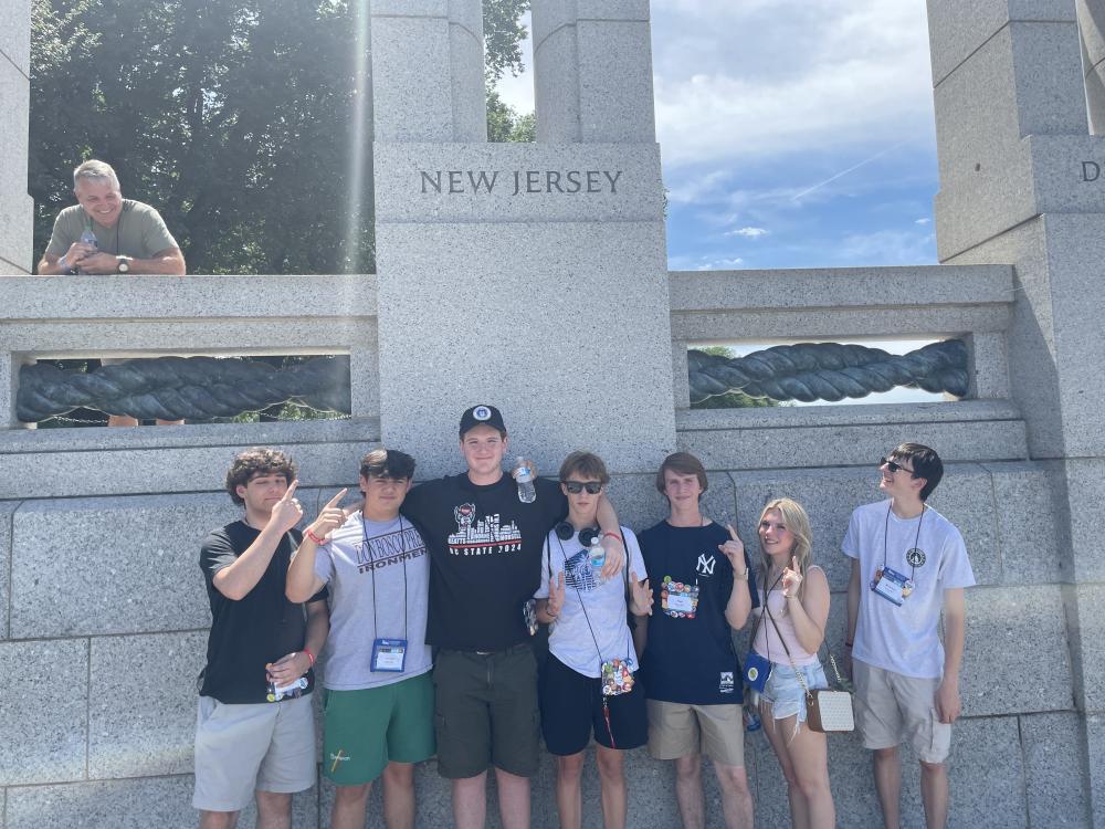 2024 Youth Tour students from New Jersey pose together in front of the New Jersey portion of the World War II Memorial