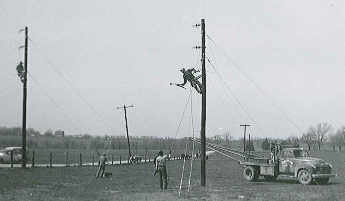 Old, black-and-white photo of early SREC line crews setting up spans of wire.