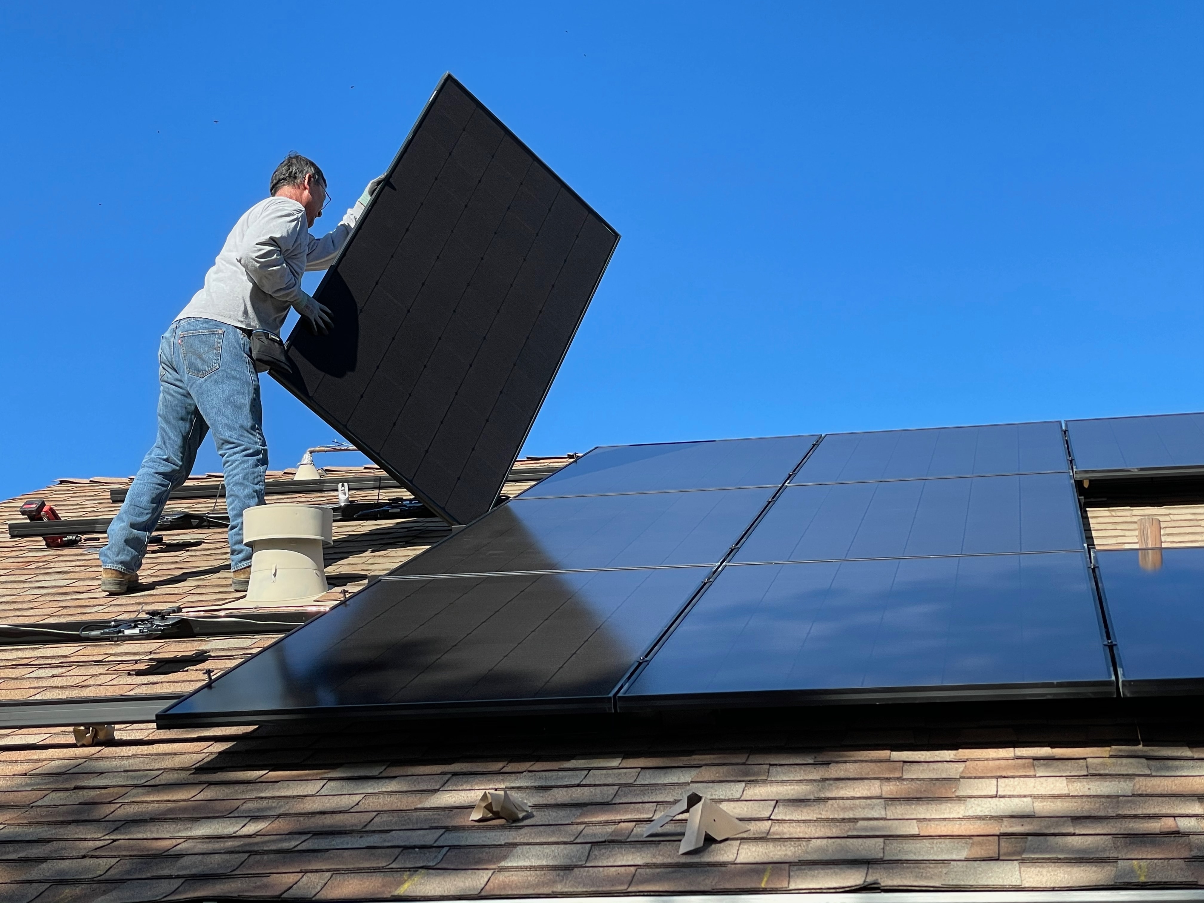 Man on rooftop installing solar panels