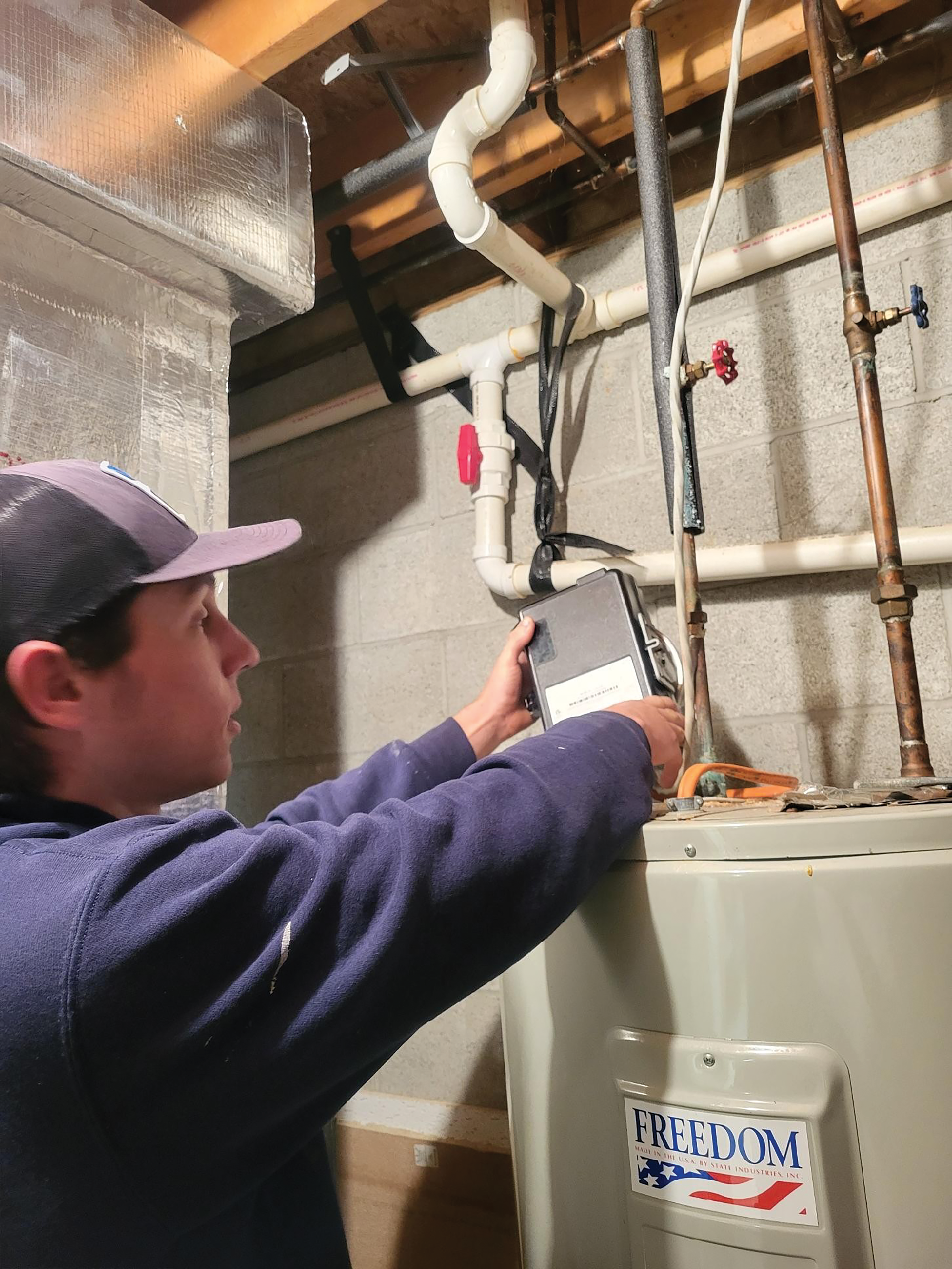 BEATING THE PEAK: Steve Tataleba, an HVAC technician at Somerset Rural Electric Cooperative, installs a load control receiver (LCR) on a cooperative member's water heater.