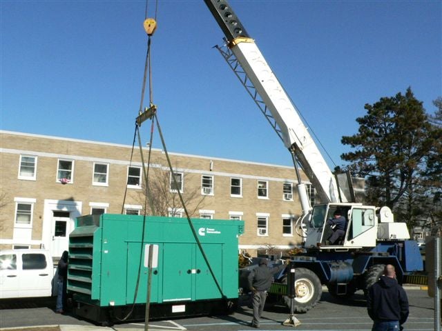 SREC Resources staff using a large crane to install a back-up generator at Centenary College